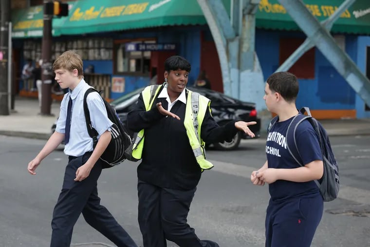 School crossing guard Aiesha Burton talks with students as they cross Kensington and Lehigh in Philadelphia, PA on June 6, 2018.