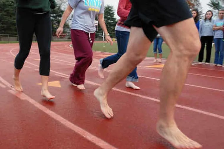 A barefoot Chris McDougall leads members of the Lower Merion girls' cross-country team on an experimental turn around the track.