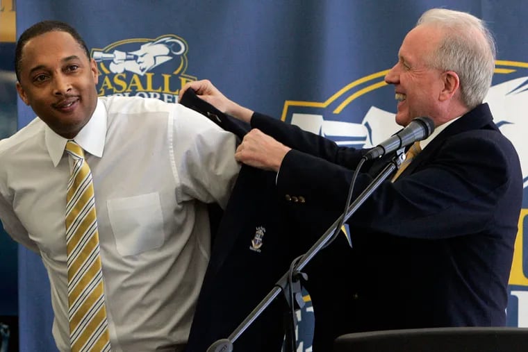La Salle athletic director Tom Brennan places a school blazer on incoming women's basketball coach Jeff Williams (left) during a news conference on March 24, 2010.