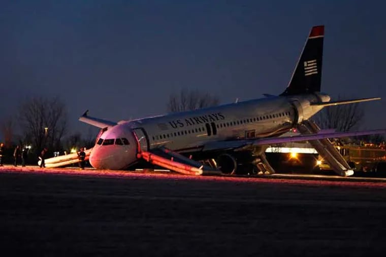 Investigators work near a damaged US Airways jet at the end of a runway at the Philadelphia International Airport. (AP photo)