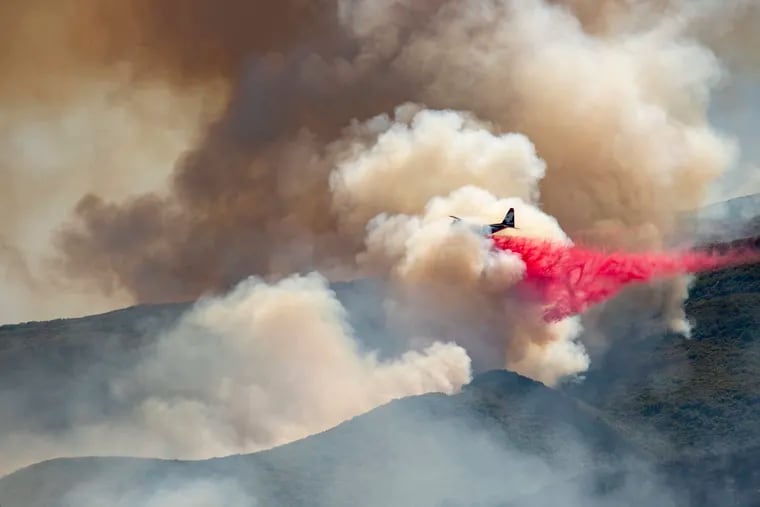 A plane drops fire retardant on a hillside in an attempt to box in flames from a wildfire during the Sand Fire in Rumsey, Calif. on June 9. Climate change for years has fueled fires that foul the air, affecting children with asthma particularly, writes the author, who grew up in California and is now studying public health in Philadelphia. (AP Photo/Josh Edelson)