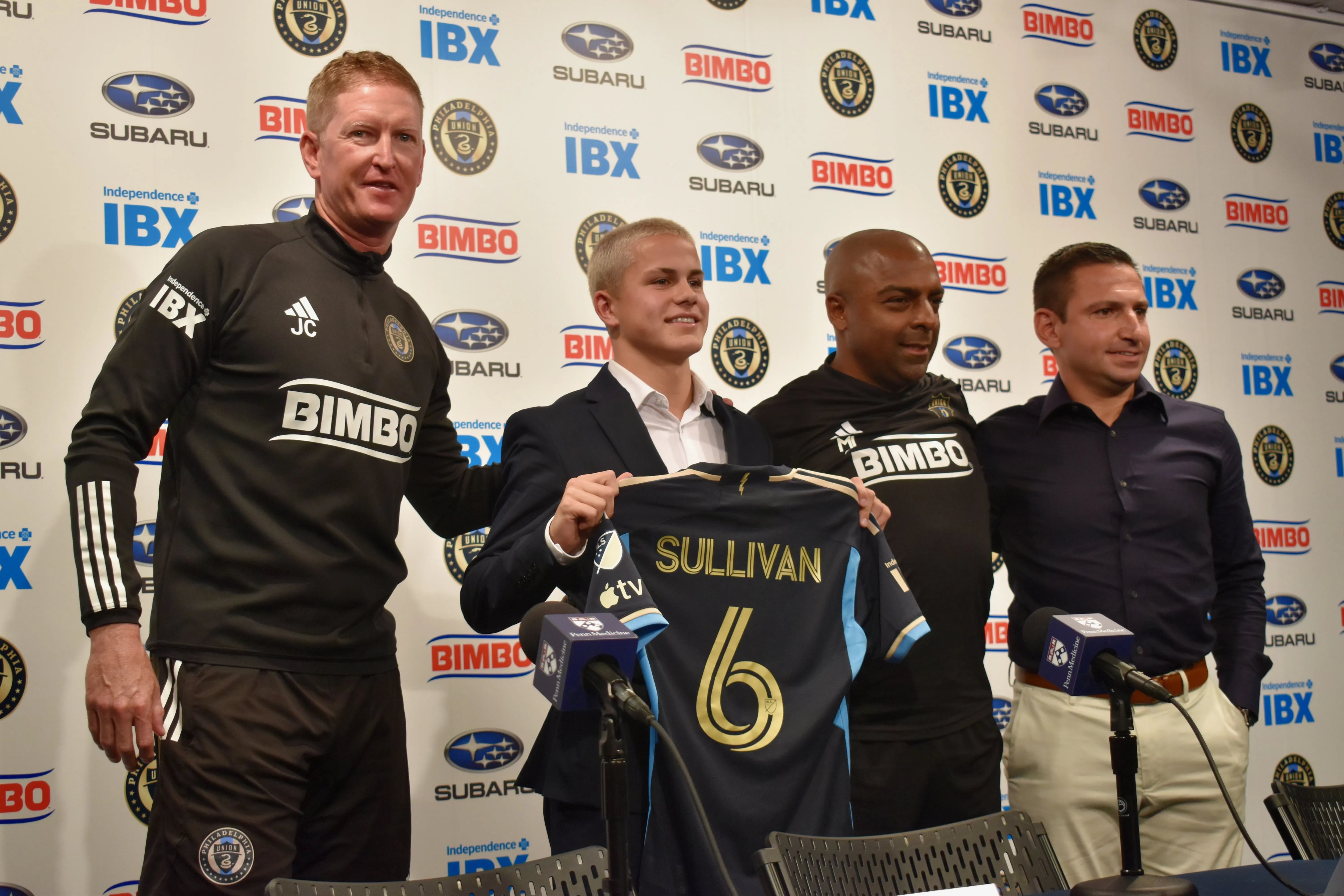 From left to right: Union manager Jim Curtin, Cavan Sullivan, reserve team coach Marlon LeBlanc, and academy director Jon Scheer pose for a photo as Sullivan holds up his new No. 6 jersey after a news conference Thursday at Subaru Park.