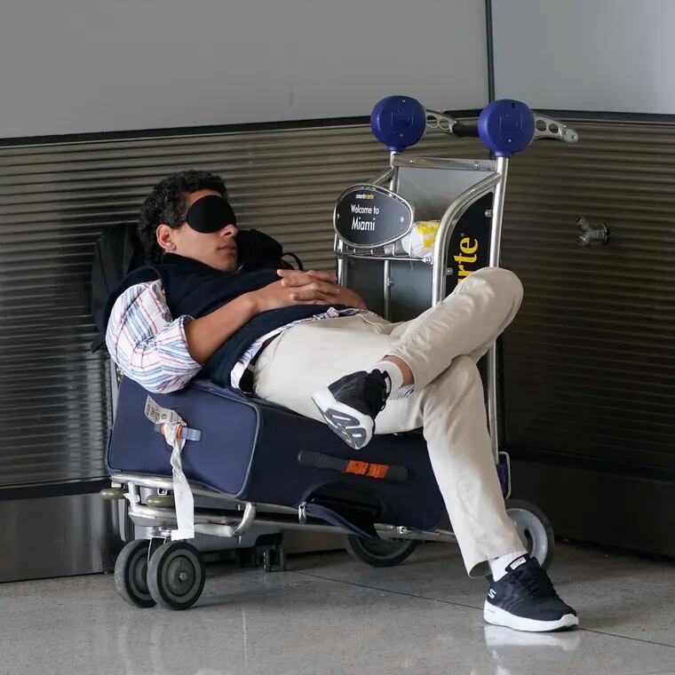 A traveler takes a nap as he waits for a ride outside Miami International Airport, in 2022.