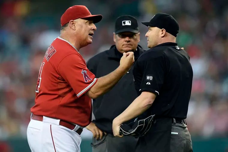 Former Angels manager Mike Scioscia talks to home plate umpire Mike Estabrook. Scioscia stepped away from the Angels after last season.