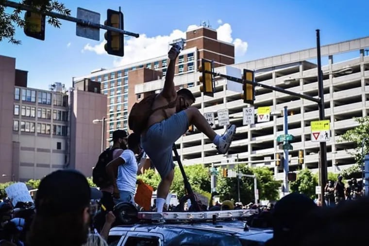 A man who Pennsylvania State Police have identified as Francisco "Franky" Reyes stomps on one of the two squad cars he is accused of vandalizing May 30 near the intersection of Broad and Vine Streets. He later shared this photo on Instagram, which police used to help identify him.