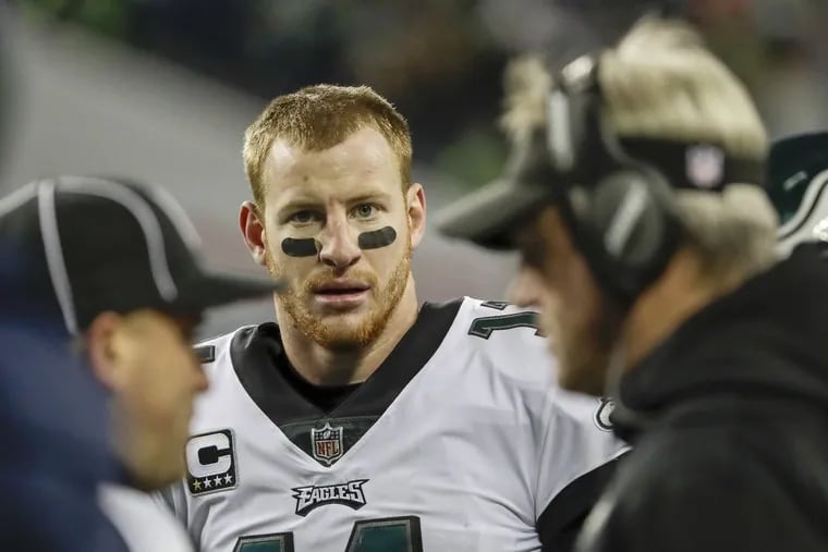 Philadelphia Eagles quarterback Carson Wentz watches head coach Doug Pederson talk to a field official during Sunday night’s game against the Seattle Seahawks.