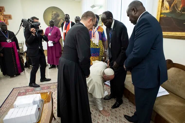 Pope Francis kneels to kiss the feet of South Sudan's President Salva Kiir Mayardit, at the Vatican, Thursday, April 11, 2019. Pope Francis has closed a two-day retreat with South Sudan authorities at the Vatican with an unprecedented act of respect, kneeling down and kissing the feet of the African leaders. (Vatican Media via AP)
