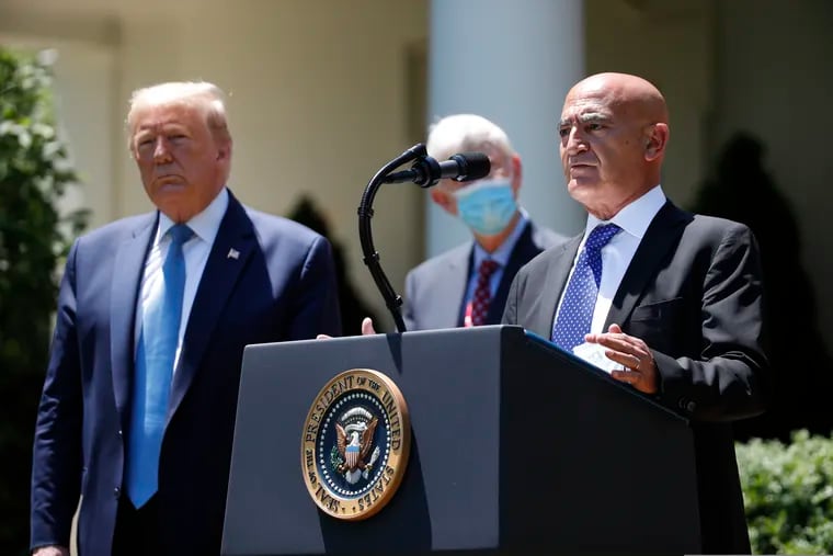 President Donald Trump (left) listens as Moncef Slaoui, a former GlaxoSmithKline executive, speaks about the coronavirus in the Rose Garden of the White House on May 15.