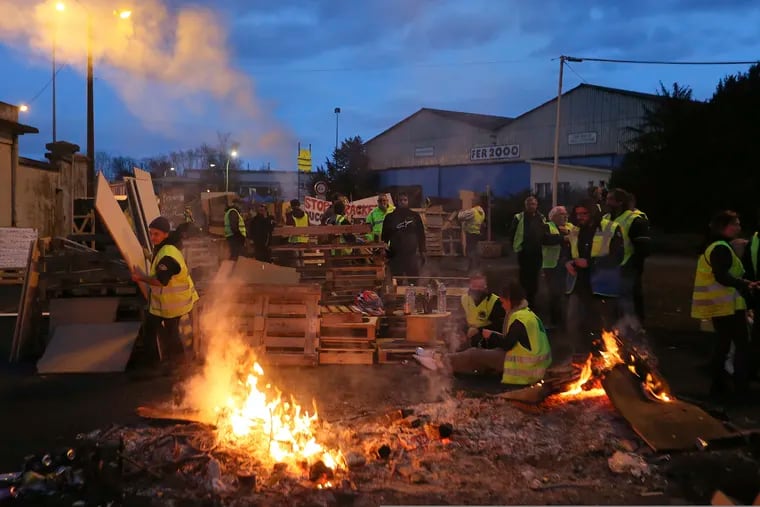 Demonstrators stand at a makeshift barricade set up by the "yellow jackets" protesters to block the entrance of a fuel depot in Le Mans, western France, on Wednesday.