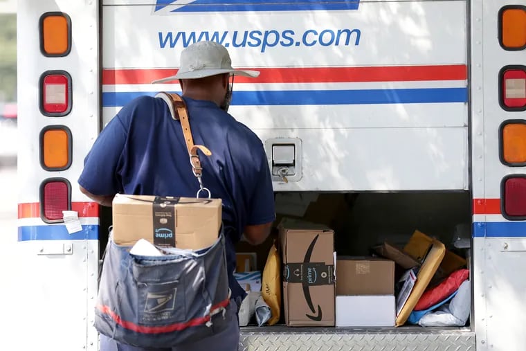 A mail carrier pulls mail from his vehicle in Millbourne, Delaware County, in August.