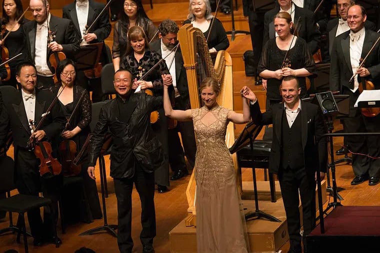 Composer Tan Dun, harpist Elizabeth Hainen, and conductor Yannick Nezet-Seguin take a bow in Beijing during the Philadelphia Orchestra's 2014 tour of China.