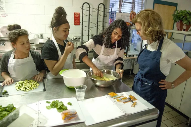Inquirer Food Editor Maureen Fitzgerald watches as Brittany Jordan stirs up the vegetable quiche ingredients in a big bowl as fellow Roberto Clemente Middle School  classmates Tatiana Castillo (left) and Emily Gonzalez watch.