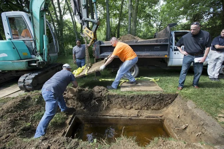 Workers remove the concrete top of a vault at King Cemetery, in Richmond, Indiana during the search for the body of Nicholas Zizzamia, who disappeared from Cherry Hill in 1979.