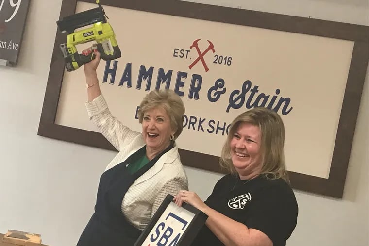 (Left, brandishing nail gun:) Pro wrestling mogul Linda McMahon now heads the Small Business Administration, where she acts as a cheerleader for Trump administration tax cuts and pro-business policies. On Aug. 8, 2018, McMahon visited Christine Smolenak (pictured), head of a family group that opened a licensed Hammer & Stain workshop for group events in Holland, Bucks County, in March, after participating in an SBA training program. McMahon also visited Steve's Prince of Steaks, a Northeast Philly-based cheesesteak chain that borrowed $150,000 from Bank of America, half guaranteed by SBA at 6%, six years ago; Victory Gardens Inc., Warminster, a 65-employee plant nursery and supply center, which borrowed $3.5 million from Fulton Bank in 2006 with a $2.7 million 6% SBA guarantee; and radio station WPHT-AM in Philadelphia