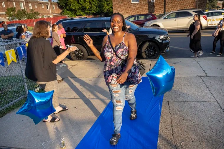 Tiffany Johnson, 4th-grade math teacher, celebrates on the blue carpet as she and other teachers and staff return to the school on their first day of work for the 2022-23 school year.