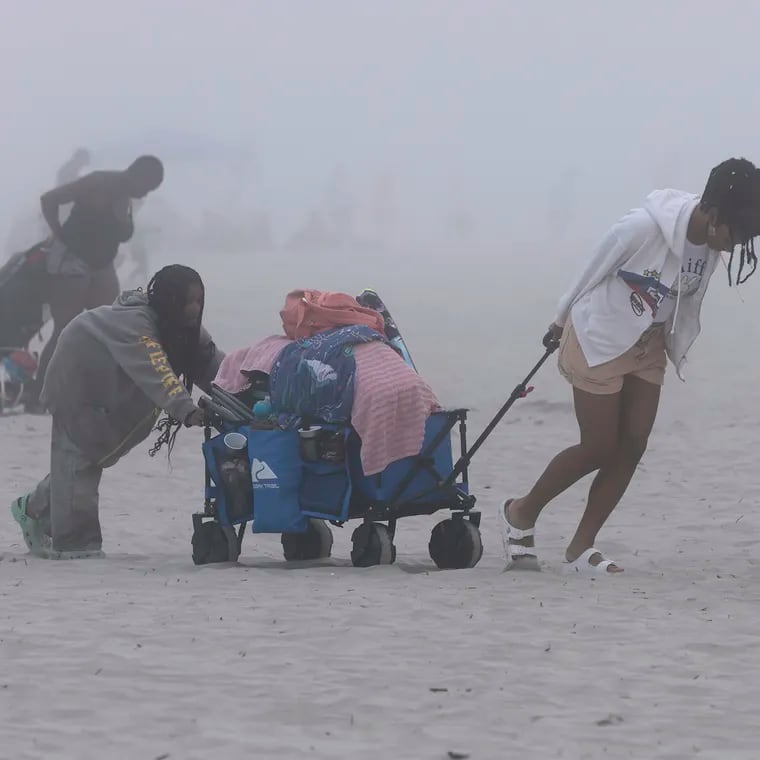 As the fog moves in Caleesi Cohen, 10, (left) and her sister Senaia-Imani Cohen, 17, move out after spending the day on the beach with their family in Wildwood.