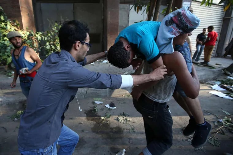 Opponents of ousted President Mohammed Morsi carry an injured friend, hurt in clashes with Morsi supporters in Cairo.