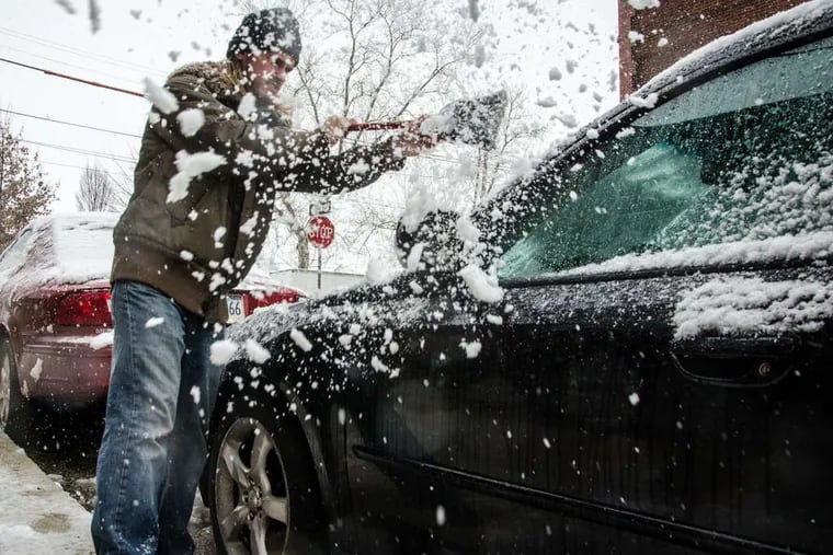 Alex Udowenko of West Philadelphia clears snow from his car. Totals of up to seven inches were reported throughout the region by evening. But the snow was not expected to stay around long.