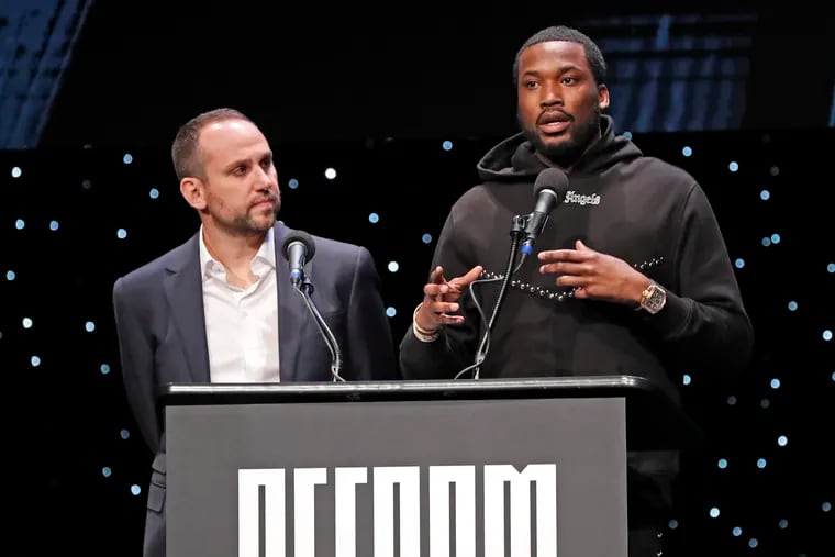 Philadelphia 76ers co-owner and Fanatics executive Michael Rubin, left, listens as recordng artist Meek Mill speaks at the launch of a partnership of sports, business and recording artists who hope to transform the American criminal justice system, Wednesday, Jan. 23, 2019, in New York. (AP Photo/Kathy Willens)