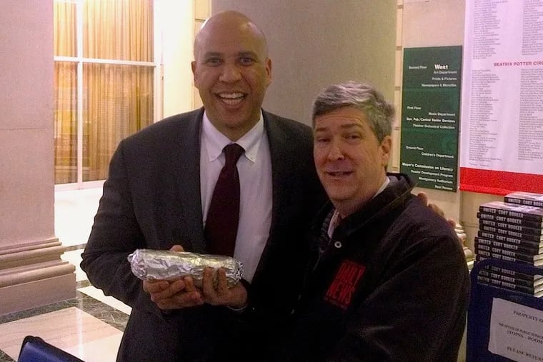 Senator Cory Booker (left) smiles upon receiving a vegan cheesesteak made by Rich Landau at Vedge restaurant, and delivered to him at the Free Library by V for Veg columnist Vance Lehmkuhl.
