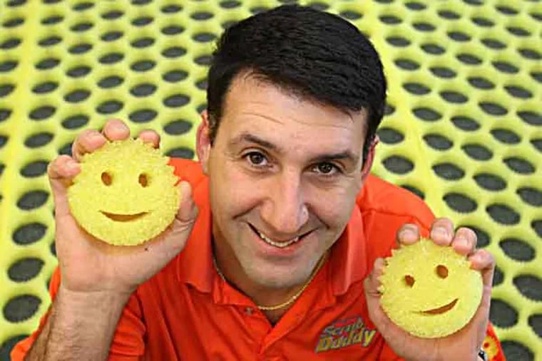 A year ago, Aaron Krause was a little-known guy from Voorhees with a goofy sponge fashioned in the shape of a smiley face.  But now after appearances on Shark Tank, Good Morning America, and QVC, Krause's Scrub Daddy is taken off.  He is shown with his sponge with sheets that the sponges were cut out from behind him.
 ( Charles Fox / Staff Photographer )