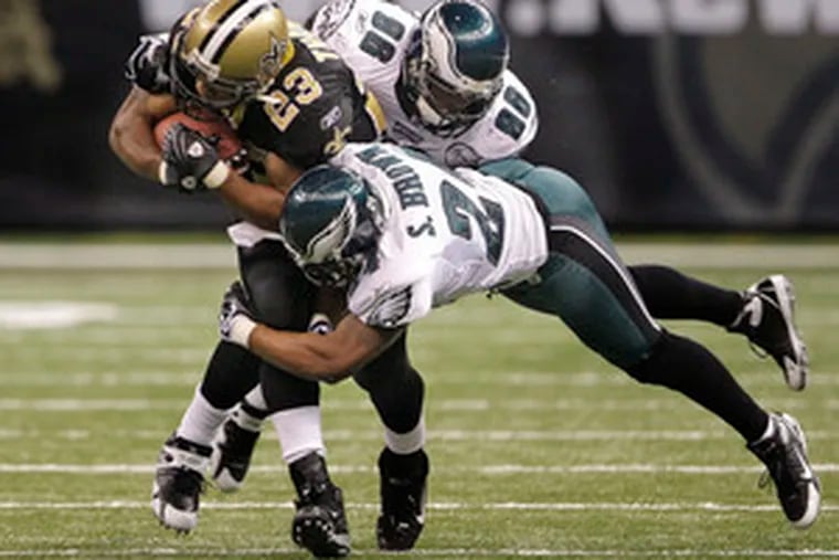 Eagles linebacker Omar Gaither gets some help from cornerback Sheldon Brown in bringing down the Saints&#0039; Pierre Thomas.