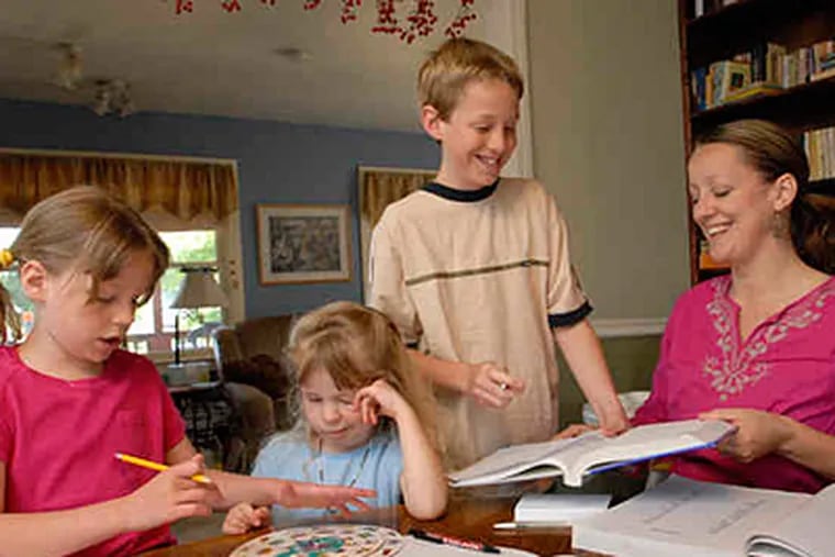 Gena Conley works with Jessa, 7, Ellie, 4, and Gabe, 11 , in their dining room. She loves the autonomy and family time that homeschooling allows. (April Saul / Staff)