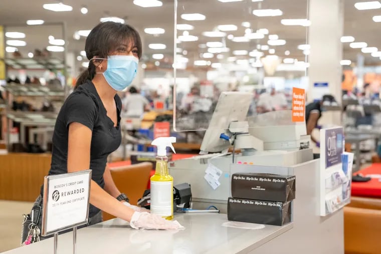 Esther Iglesias, a sales clerk in the shoe department at Boscov's at Plymouth Meeting Mall, wipes the counter before a customer arrives at her register earlier this month.