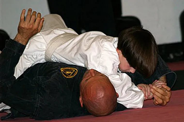 This June 2010 photo provided by Lisa Suhay shows her son Quin Suhay, now 8, tackling Bill Odom, owner of Norfolk Karate Academy in Norfolk, Va., as part of a bullyproofing class. (AP Photo/Lisa Suhay)
