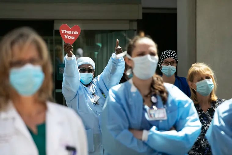 A health-care worker holds up a "Thank You" sign while Connecticut Gov. Ned Lamont speaks outside Saint Francis Hospital in Hartford, Conn., in this May 7, 2020, file photo. Health-care workers and families are seeking more than appreciation for their sacrifices. (AP Photo/Mark Lennihan, File)