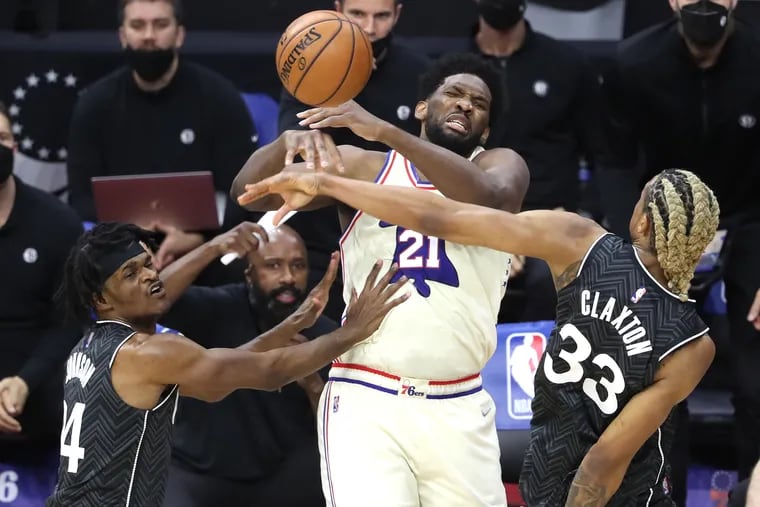 Sixers center Joel Embiid has the ball stripped away by the Nets' Alize Johnson (left) and Nicolas Claxton of the Nets during the Sixers' 123-117 victory Wednesday.
