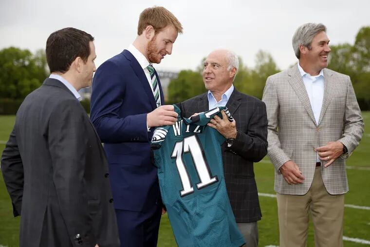 Eagles first-round pick Carson Wentz held his jersey while with (from left) Howie Roseman, Jeffrey Lurie and coach Doug Pederson the day after the 2016 draft.