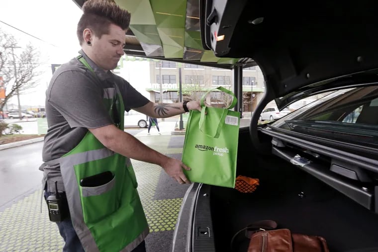 An Amazon worker, who declined to be identified, loads a bag of groceries into a customer&#039;s car trunk at an AmazonFresh Pickup location, Tuesday, March 28, 2017, in Seattle.