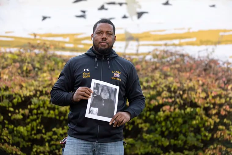 Head football coach Malik Jones posed for a portrait with a photograph of his dad outside of Martin Luther King High School on Nov. 29. Jones coached his team to a win on Thanksgiving, just a few days after his father’s funeral.
