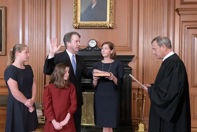Chief Justice John Roberts, right, administers the Constitutional Oath to Judge Brett Kavanaugh in the Justices' Conference Room of the Supreme Court Building. Ashley Kavanaugh holds the Bible. In the foreground are their daughters, Margaret, left, and Liza.