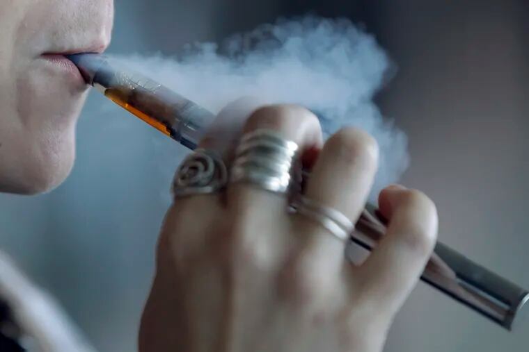 A woman exhales while using a vaping device.