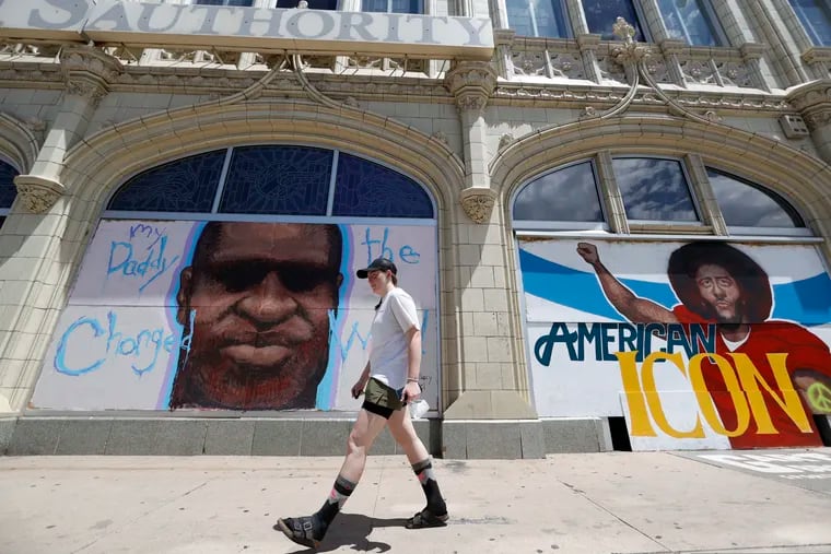 A pedestrian passing murals to honor George Floyd and former NFL quarterback Colin Kaepernick covering pieces of plywood used to shield windows in an empty storefront south of the State Capitol in Denver, Colo., last June.