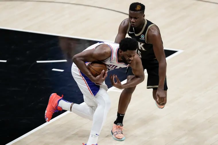 Sixers center Joel Embiid holds the basketball while defended by Atlanta Hawks center Clint Capela in Game 4 of the NBA Eastern Conference playoff semifinals on Monday in Atlanta.