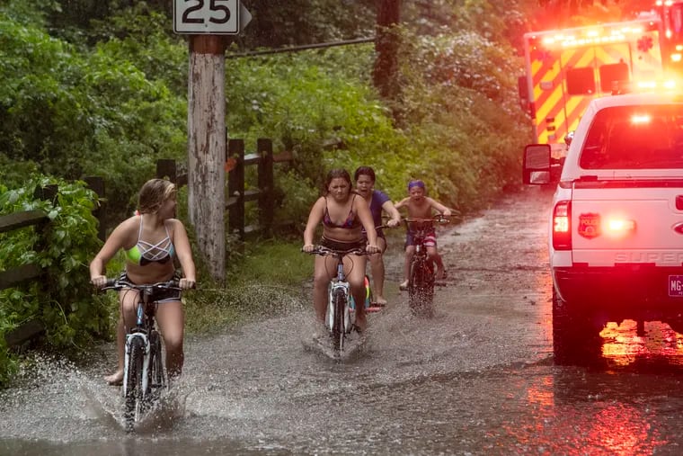 Kids that live near the banks of the Schuylkill river ride their bicycles along Nixon St. as rescue personal arrive at scene.   Philadelphia Fire and Police respond to unknown incident near Nixon, River Road at bottom of Shawmont Ave in Shawmont Valley section of Philadelphia during heavy rain and flooding cause by tropical storm Isaias on Tuesday, August 4, 2020. This area is on the banks of the Schuylkill River.