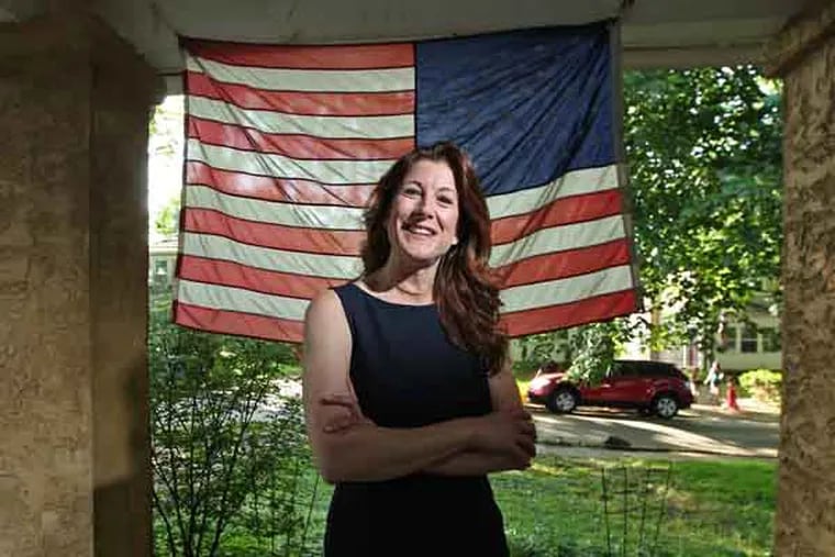 Denise Logsdon on the front porch of her Springfield home. Her family is in the Navy, her husband's Army so they fly the flag enthusiastically.  Denise Logsdon, 45, of Springfield, who will walk in DCCC's graduation on the 23rd despite having had a major operation in April for cancer of her thyroid which left her vocal chords damaged and her right ear and portions of her scalp, neck, jaw and collarbone paralyzed. A mother of four children, Logsdon will receive an Associate of Science degree. She plans to transfer to the University of Pennsylvania, where she will study Human Rights and Social Justice. She hopes to one day pursue her Doctorate degree in Justice, Law and Policy and become a human rights advocate and policy scholar. She was also pres. of student government and the schools honor society. 05/20/2013