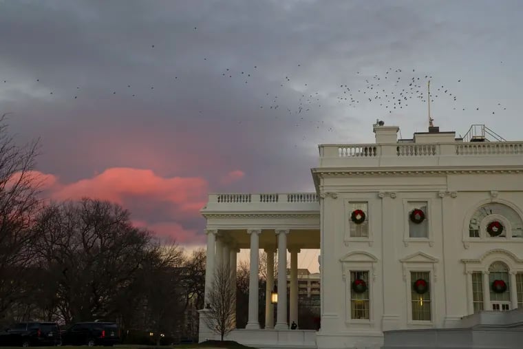 The setting sun illuminates clouds behind the White House during a partial federal shutdown, Saturday, Dec. 22, 2018, in Washington.
