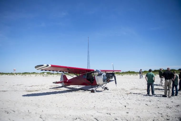 Officials examine a plane that landed on a restricted beach at the Coast Guard's Training Center in Cape May Sunday night. The pilot ran away and was still being sought Monday.