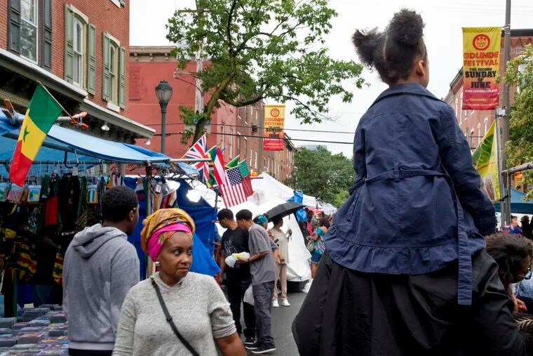 Freedom Reign, 5, rides along South Street on the shoulders of her father, Manani Akbar of Northeast Philadelphia, during the annual Odunde Street Festival along South Street Sunday.