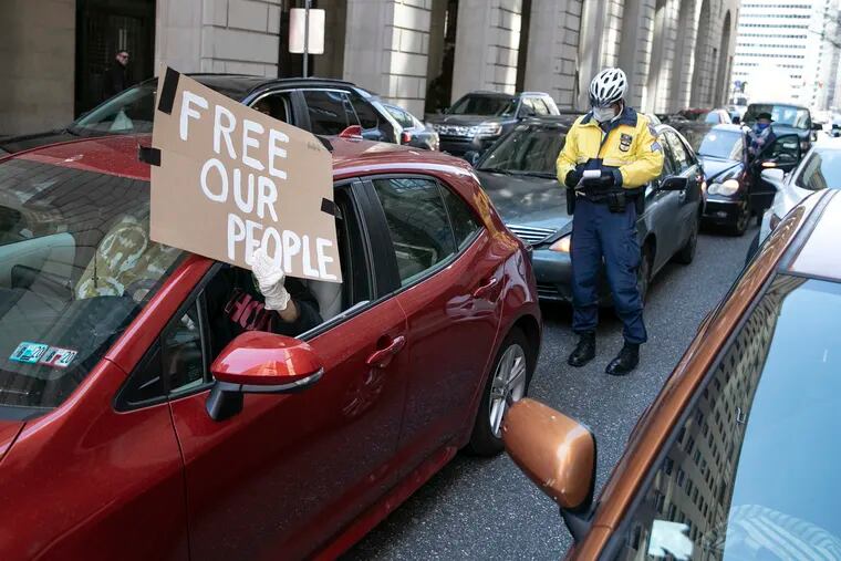 Protesters wave signs out of their car windows while Philadelphia Police ticket them outside of the Juanita Kidd Stout Center for Criminal Justice in Philadelphia in April. The protesters were there to demand the release of more inmates in city jails due to coronavirus fears.