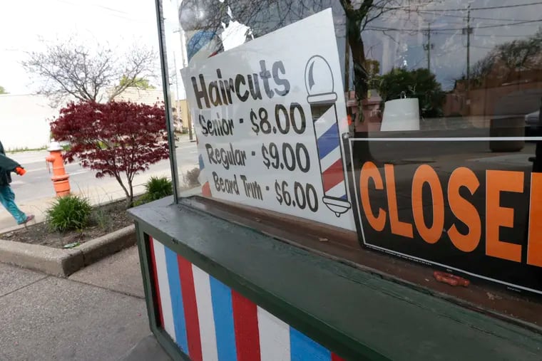 A pedestrian walks past a closed barber shop, Wednesday, May 6, 2020, in Cleveland. (AP Photo/Tony Dejak)
