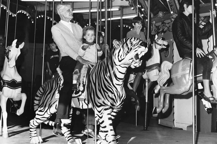 John Gretzinger, 72, of Nicetown, and his two-year-old granddaughter, Jennie McMahan, sit on a tiger during a recent test-ride of the carousel. Gretzinger says he was there when it opened 65 years ago.