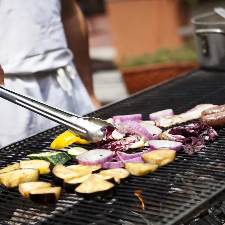 A food vendor grilling veggies and links at the Flavors on the Avenue street food festival on East Passyunk Avenue.