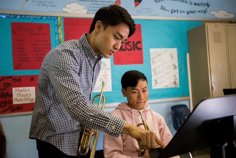 Nozomi Imamura helps South Philadelphia High School 10th-grader Alexson Sok during band class.