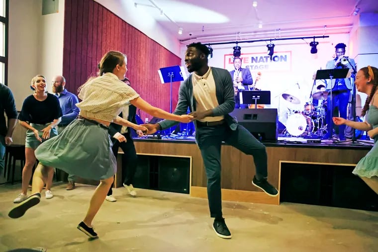 Nii Attoh-Okine (center) of Newark, Del., dances with partner Lauren Fosnight of Philadelphia as grantee Joshua Lee on saxophone plays with his band inside the Fashion District's REC Philly location in Philadelphia. The celebration of live performances and artist meet and greets marked the recognition of the 23 Black Music City grantees.