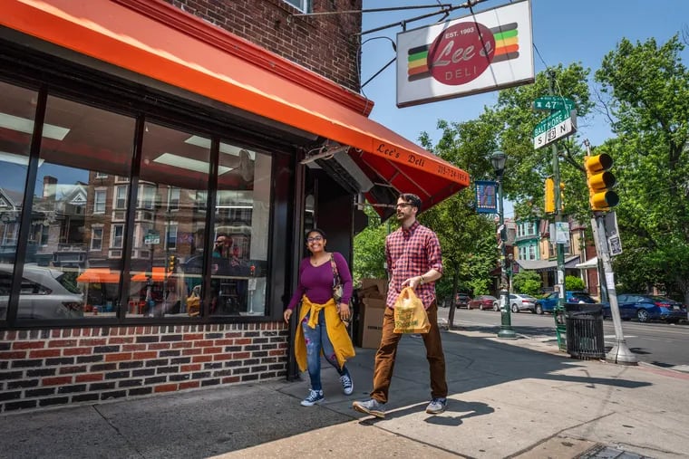 Customers carry a lunch order from the newly reopened Lee’s Deli, in Philadelphia, Thursday, May 18, 2023.